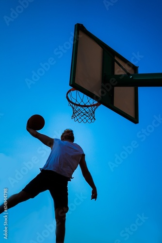 Man playing basketball over blue sky