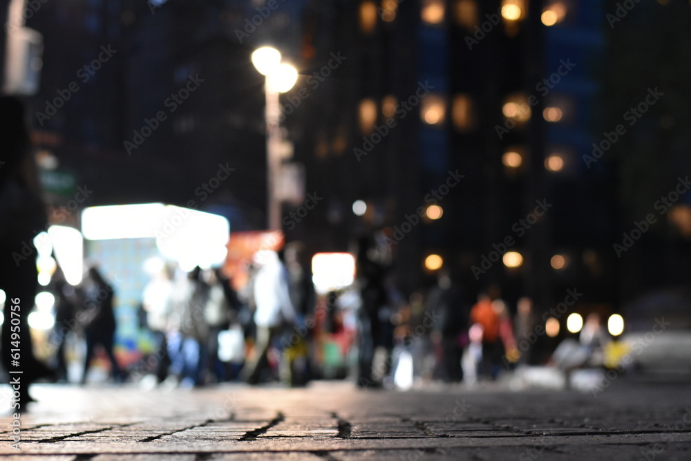 Fototapeta premium Sidewalk at Night in New York City, Blurred Pedestrians in Distance