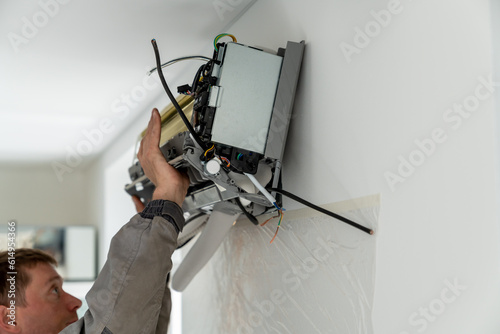 Man technician worker in uniform fixing repairing apartment air conditioner, installing wall-mounted mini split. AC unit maintenance concept