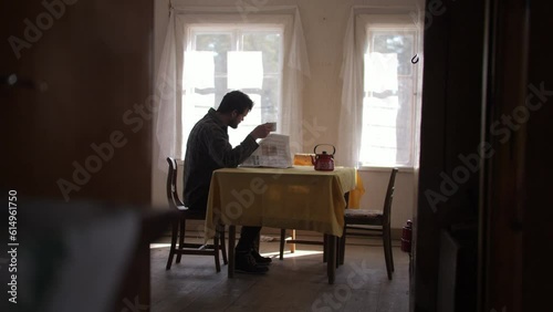 Archive old, man reading newpaper at kitchen table, low angle photo
