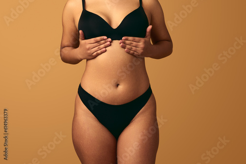 Crop plump woman with hands under breast