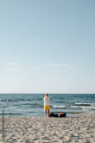 Rear view of an unrecognizable lonely old man on the beach by the sea