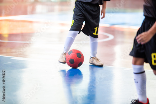 Kid futsal player control the ball for shoot to goal. Indoor soccer sports hall.
