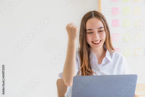 Cheerful businesswoman raising her fist delighted face, yes gesture, celebrating success after analysis graph at home office for setting challenging business new goals And planning to achieve target