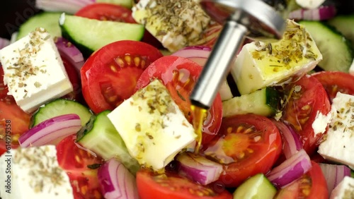 Zoom frame pouring olive oil on greek salad. Fresh vegetable salad, mediterranean cuisine