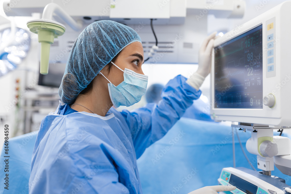Anesthesiologist keeping track of vital functions of the body during cardiac surgery. Surgeon looking at medical monitor during surgery. Doctor checking monitor for patient health status. Anesthesiologist keeping track of vital functions of the body during cardiac surgery. Surgeon looking at medical monitor during surgery. Doctor checking monitor for patient health status.