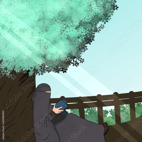 a Muslimah wearing a niqab cadar is reading under a shady tree photo