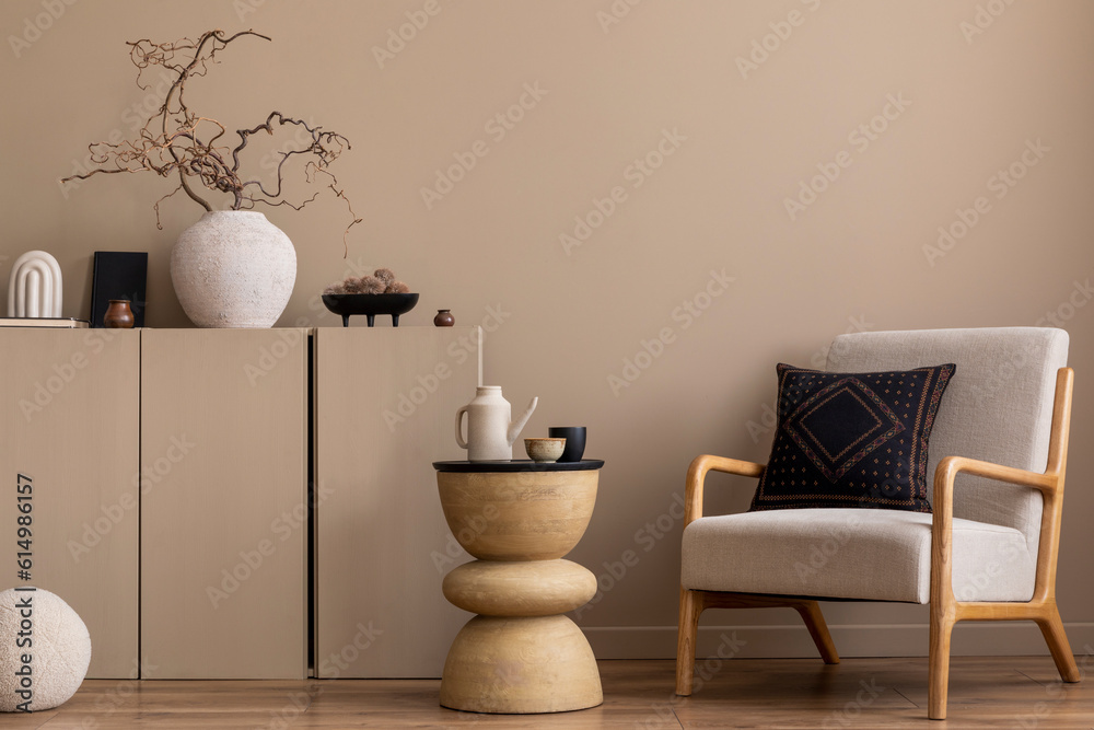 Cozy composition of living room interior with gray armchair, dark pillow, beige sideboard, wooden coffee table, vase with branch, round pillow and personal accessories. Home decor. Template. Cozy composition of living room interior with gray armchair, dark pillow, beige sideboard, wooden coffee table, vase with branch, round pillow and personal accessories. Home decor. Template.