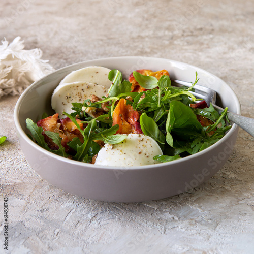 bowl with salad with peaches, arugula and mozzarella on the table