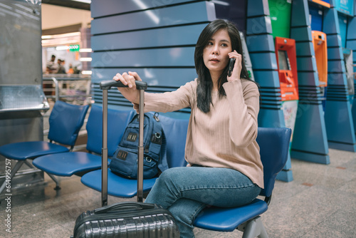 Portrait of Attractive Asian Woman Using Smartphone Checking Flight Schedules at Airport Terminal, Technology on Mobile Phone, Social Media, Lifestyle concept.