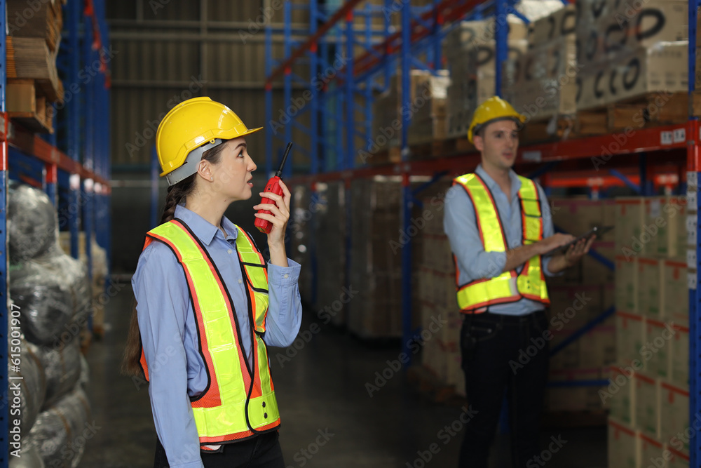 Group of warehouse workers with hardhats and reflective jackets using tablet, walkie talkie radio and cardboard while controlling stock and inventory in retail warehouse logistics, distribution center Group of warehouse workers with hardhats and reflective jackets using tablet, walkie talkie radio and cardboard while controlling stock and inventory in retail warehouse logistics, distribution center