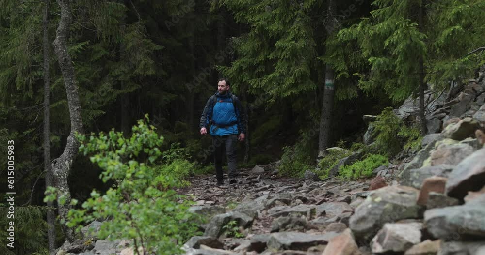 A fit young man is walking alone on a rocky terrain, coming out of the forest. The concept of a man traveling alone. A fit young man is walking alone on a rocky terrain, coming out of the forest. The concept of a man traveling alone.