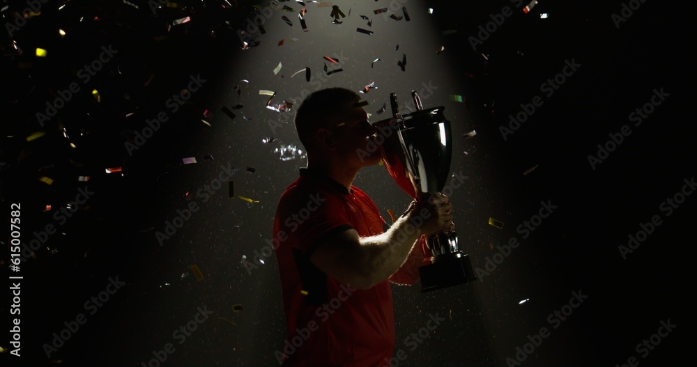 Silhouette of Caucasian male rugby player raising a trophy above head against bright light and falling confetti. Super slow motion, shot on RED cinema camera Silhouette of Caucasian male rugby player raising a trophy above head against bright light and falling confetti. Super slow motion, shot on RED cinema camera