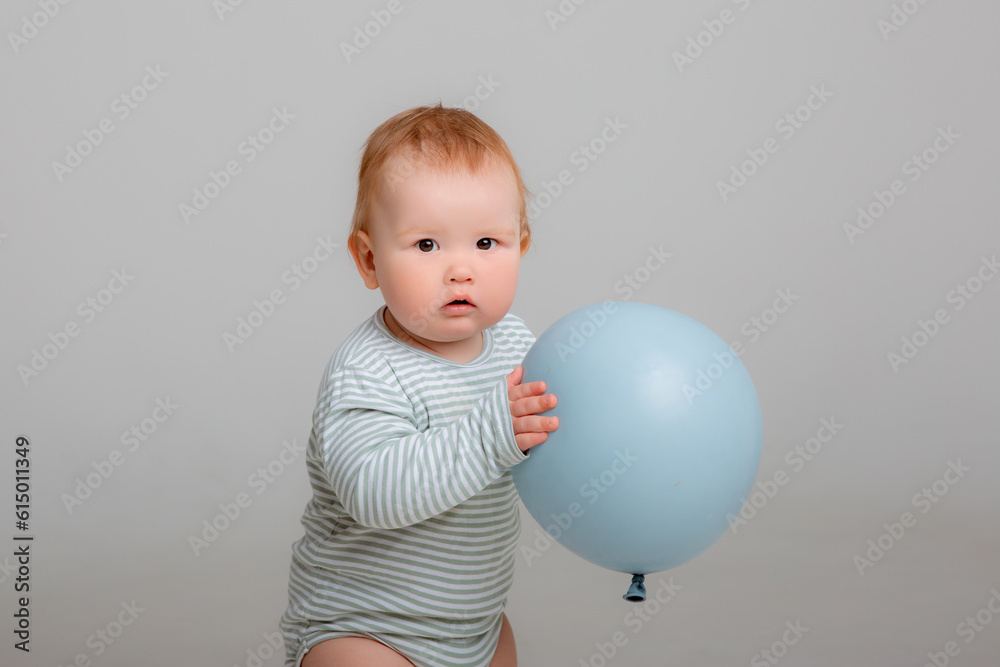 baby boy stands holding a balloon on a white background baby boy stands holding a balloon on a white background