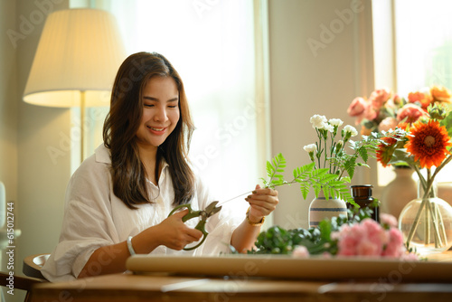 Shot of pretty female florist preparing bouquet of pink flowers at table in flower shop. Floristry and small business concept