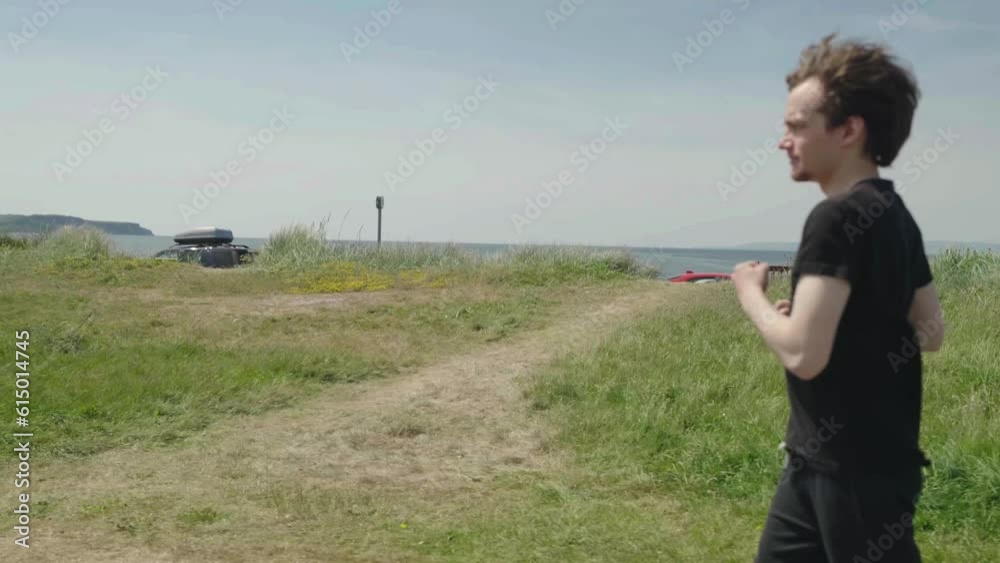 Adult male jogging with green field and blue sky in background, slow mo Adult male jogging with green field and blue sky in background, slow mo