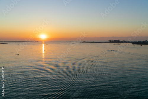 Landscape at the mouth of the river at dawn with small fishing boats in the distance. Taken from above.