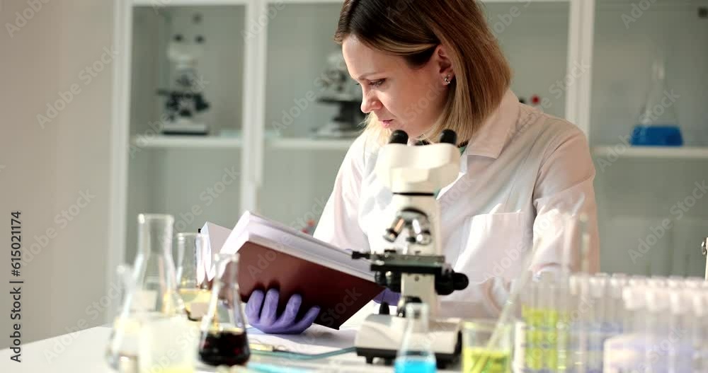 Young woman scientist reads book in laboratory. Biologist doing laboratory research Young woman scientist reads book in laboratory. Biologist doing laboratory research