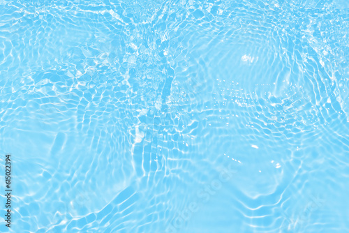 Blue water with ripples on the surface. Defocus blurred transparent blue colored clear calm water surface texture with splashes and bubbles. Water waves with shining pattern texture background.