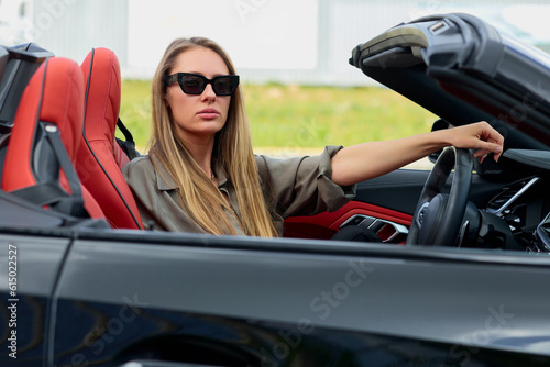 Professional woman savouring the feeling of accomplishment in her newly acquired convertible car