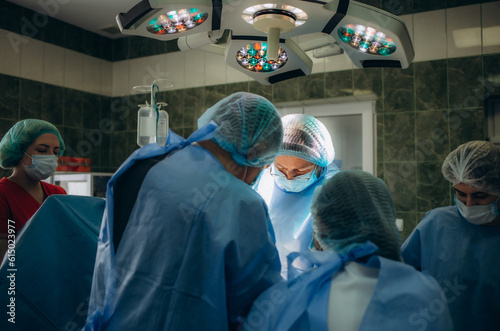 Surgical team performing surgery in modern operation theater,Team of doctors concentrating on a patient during a surgery,Team of doctors working together during a surgery in operating room,