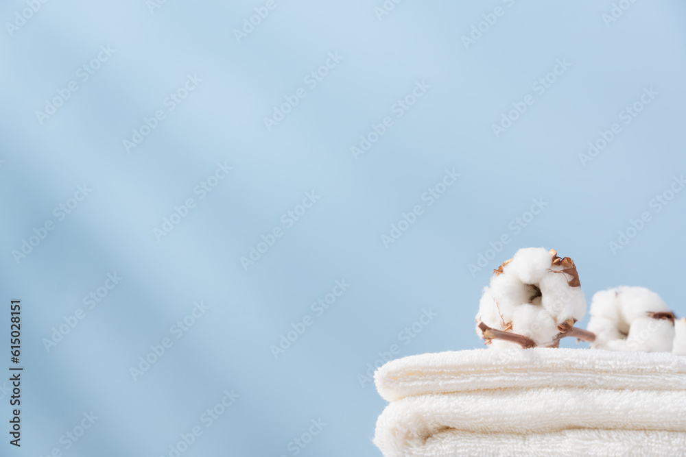 Stack of organic cotton terry towels on blue background with copy space. Delicate textiles, bath accessories Stack of organic cotton terry towels on blue background with copy space. Delicate textiles, bath accessories
