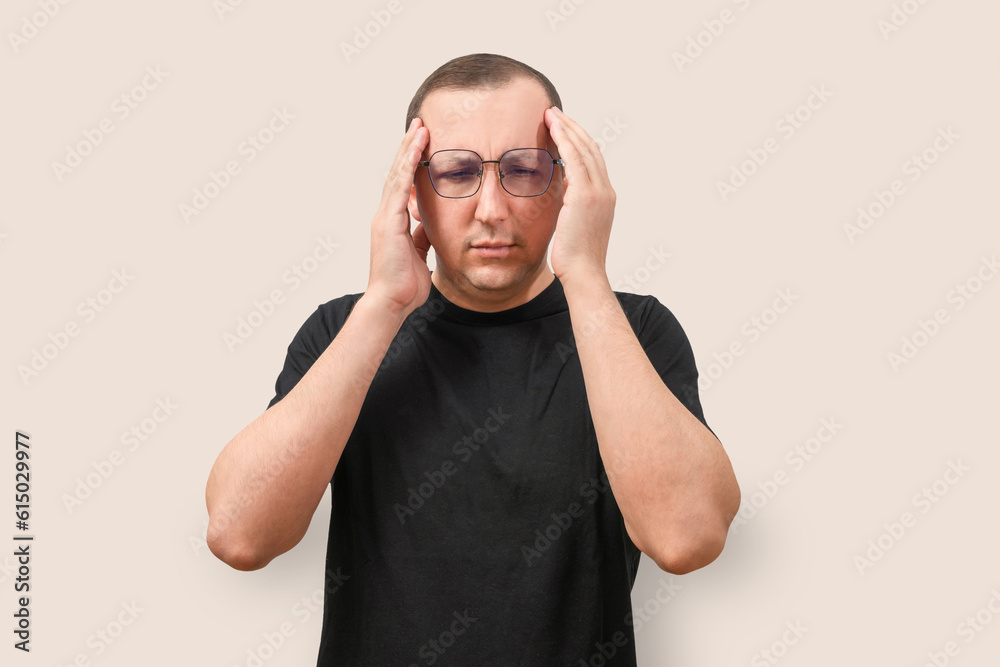 Portrait of a young man with a headache on a beige background. Health care and medicine