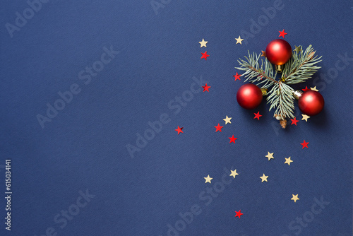 Christmas card banner with red round balls toys, Christmas tree branches, glitter stars. Mockup for your congratulations. Blue background. 
