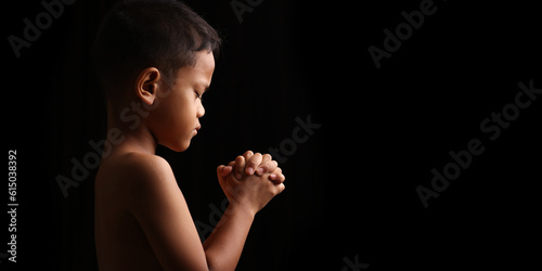 Portrait of praying boy on dark background