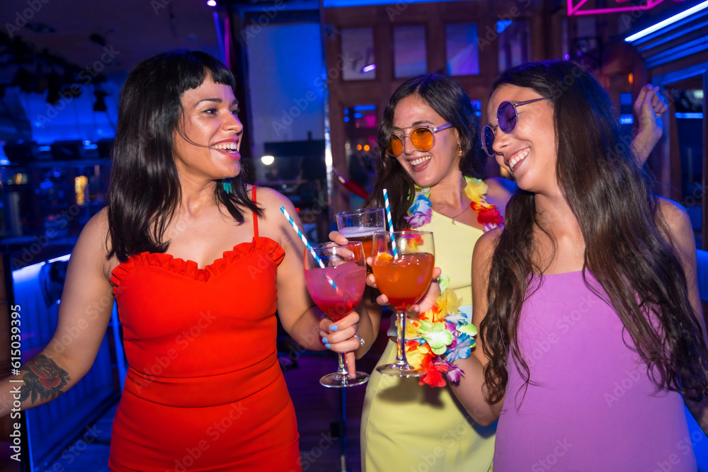 Female friends in a nightclub having fun dancing at a summer night party in a pub