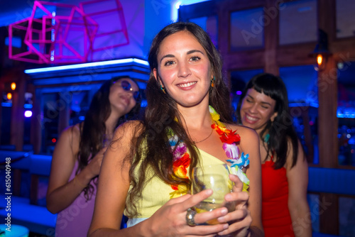 Attractive woman smiling with a glass of alcohol in a nightclub at a night party
