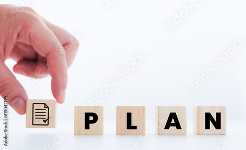 Hand drawn wooden block with the word PLAN and approval documents for business plan ideas.