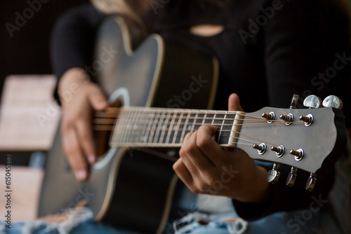 Music and hobbies. A talented young musician girl sits alone and composes songs on the guitar. The girl plays a calm melody on a musical instrument.