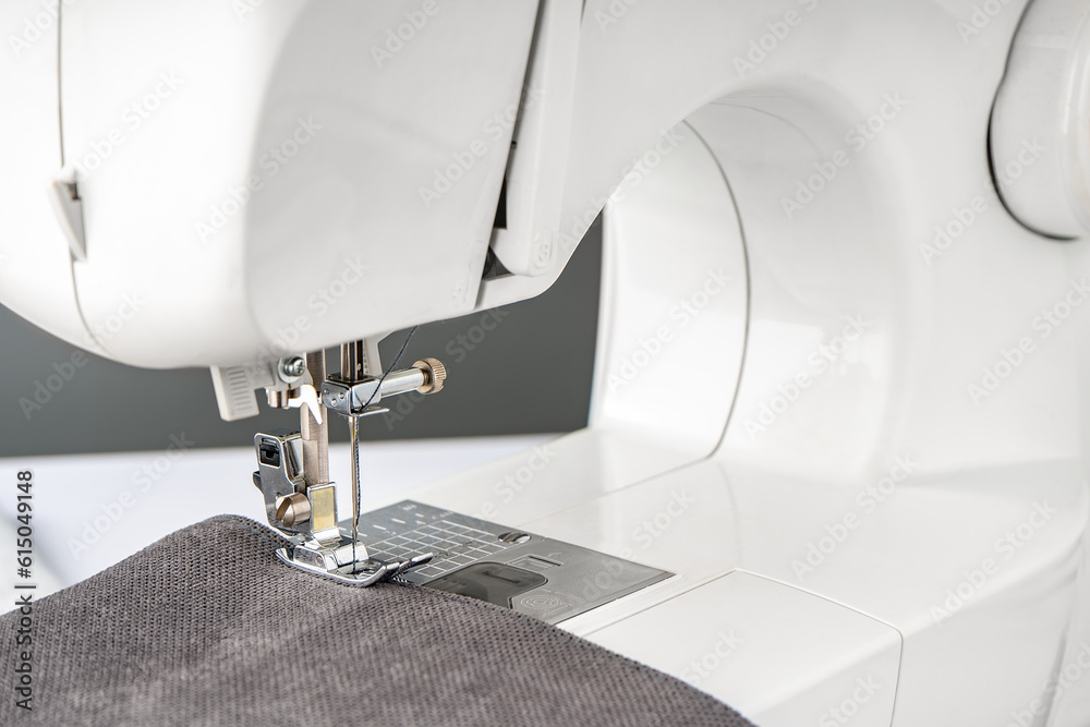 Modern sewing machine with gray fabric and. Sewing process clothes, curtains, upholstery. Business, hobby, handmade, zero waste, recycling, repair concept