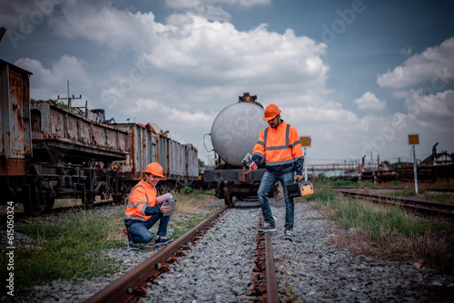 Engineer railway under inspection and checking construction railway switch and maintenance work on railroad station by blueprint and tablet .Engineer wearing safety uniform and safety helmet in work. photo