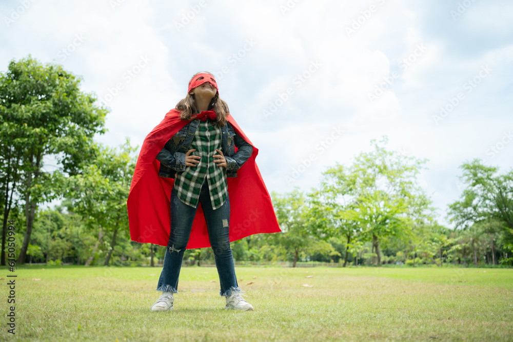 On a beautiful day in the park, a young girl enjoys her vacation. Playful with a red superhero costume and mask. On a beautiful day in the park, a young girl enjoys her vacation. Playful with a red superhero costume and mask.