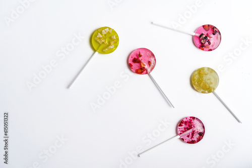 pink and yellow lollipops with pieces of fruit alternating in color laid in random order on a white background