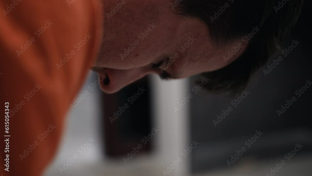 Anxious, nervous man wringing hands, sad, depressed attractive, handsome man, criminal prisoner, inmate in orange jumpsuit sitting in prison cell. Anxious, nervous man wringing hands, sad, depressed attractive, handsome man, criminal prisoner, inmate in orange jumpsuit sitting in prison cell.