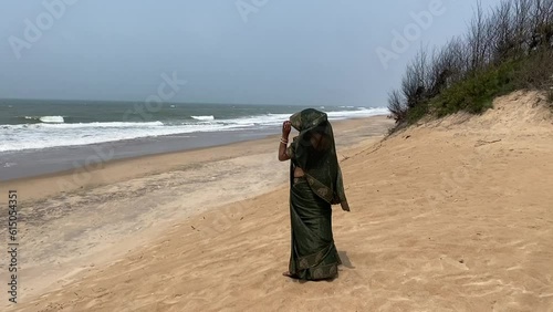 An Indian woman in green saree standing near a yellow beach at Konark Sun Temple, Orissa. photo