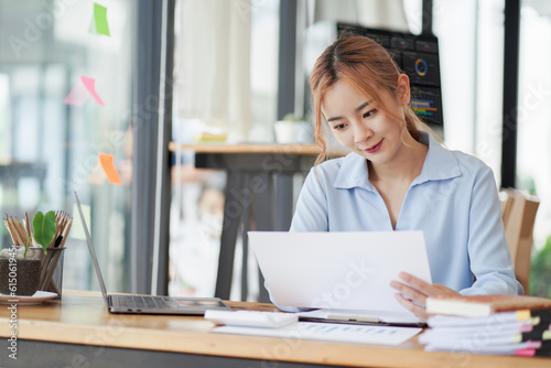 A businesswoman or accountant is using a calculator to work on financial investments, analyzing business and marketing growth on a financial document data graph.