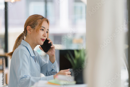 Young adult Asian businesswoman  secretary  sales manager  business consultant  engaging in a phone conversation with a client at the office.