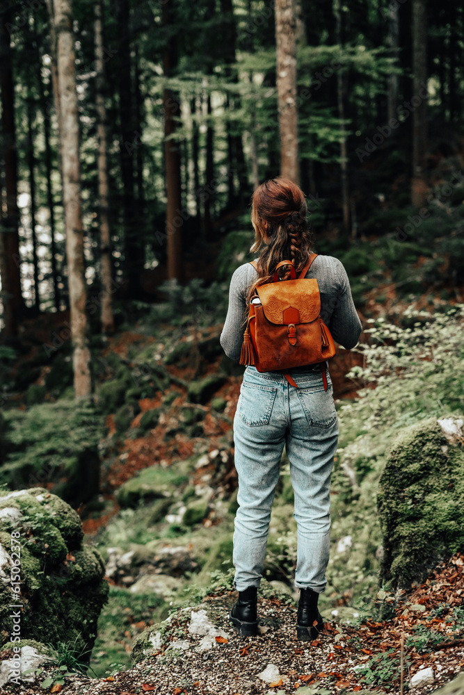 girl with a backpack about to enter a forest to explore during an autumn day girl with a backpack about to enter a forest to explore during an autumn day