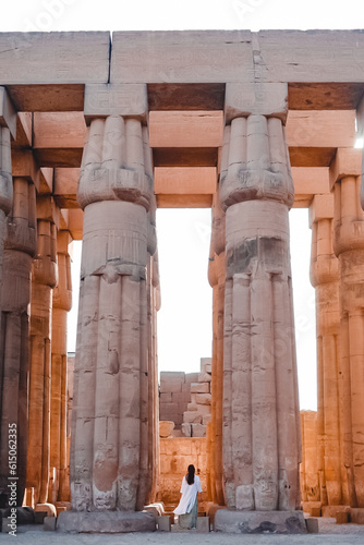 girl dressed in white between big columns in an egyptian temple