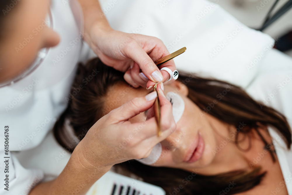 Beautiful young adult woman receiving professional eyelash makeup treatment. Cosmetician is smiling and looking at camera. Beauty and cosmetics business. Beautiful young adult woman receiving professional eyelash makeup treatment. Cosmetician is smiling and looking at camera. Beauty and cosmetics business.