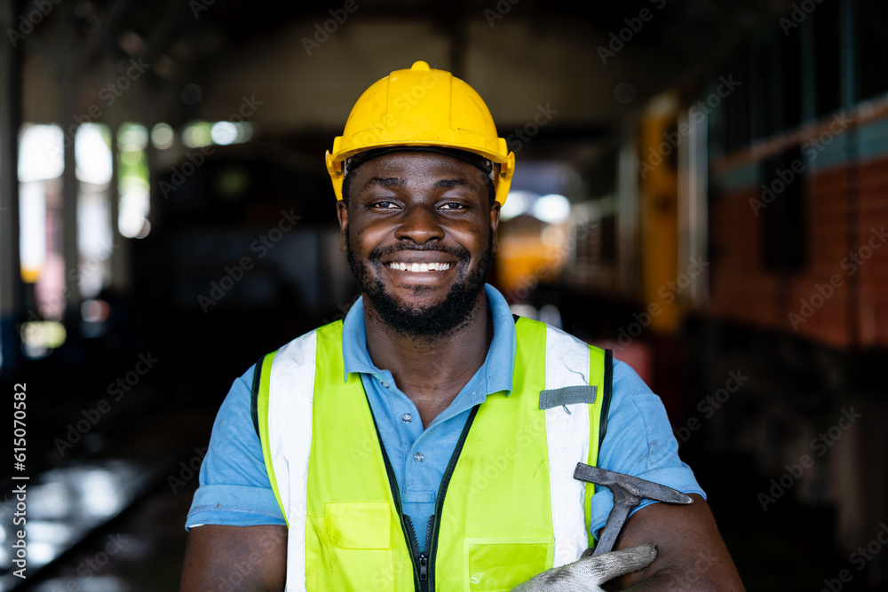 Portrait of African male railway engineer standing confidently with green safety suit and helmet. Workers working at heavy machinery at industrial plant. Portrait of African male railway engineer standing confidently with green safety suit and helmet. Workers working at heavy machinery at industrial plant.