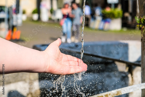 Girl's hands and flowing water at the water fountain in town