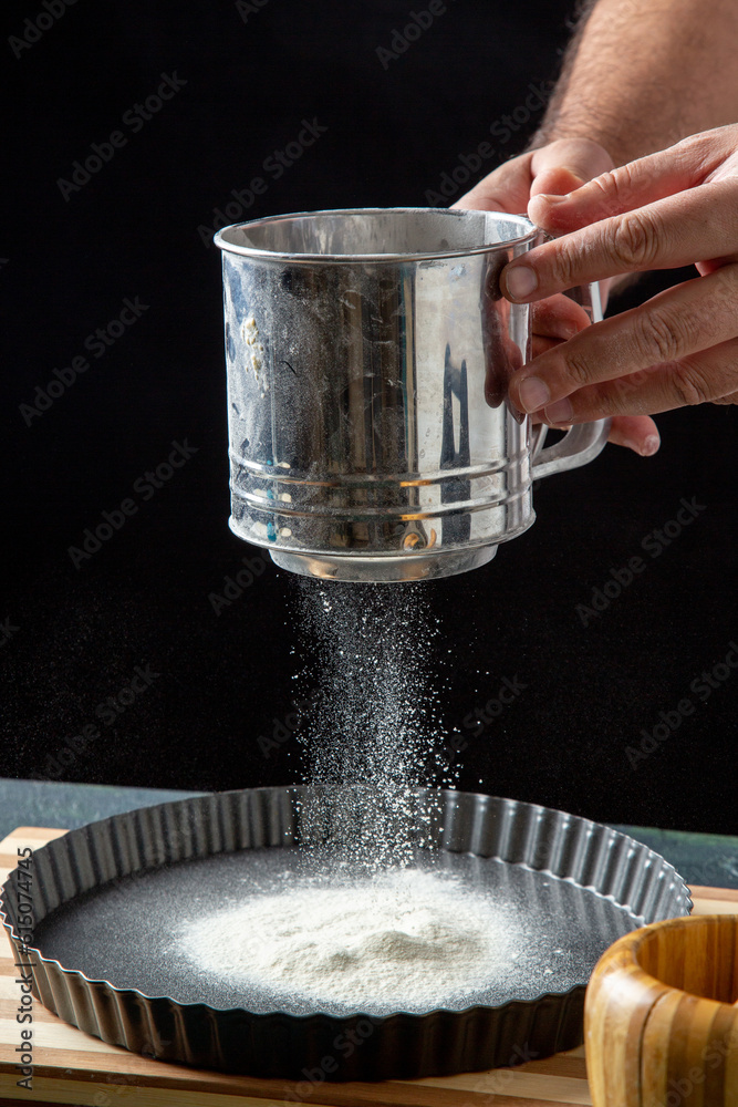 Half body shot of male chef sifting flour in the kitchen in front view Half body shot of male chef sifting flour in the kitchen in front view
