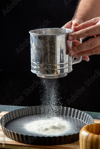 Half body shot of male chef sifting flour in the kitchen in front view