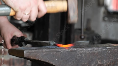 Blacksmith stokes a coal fire and pounds a red hot peice of metal with a hammer photo