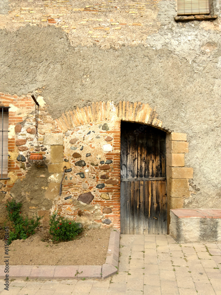 Puerta vieja de madera de casa masía medio tapiada con piedras foto de